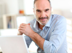 Man with grey hair and scruff smiling at camera
